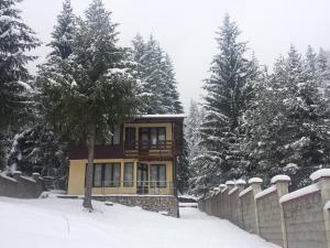 una casa en la nieve con una valla y árboles en Вила Мерджан, en Sarnitsa