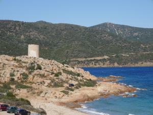 a tower on a hill next to a body of water at B&B Sa Tuerra in Teulada