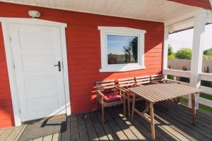 a red house with a bench and a door at Domki Letniskowe Skandynawia in Ustka