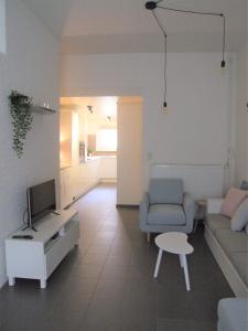 ein Wohnzimmer mit einem Sofa, einem TV und einem Stuhl in der Unterkunft Maison HB in Ypern