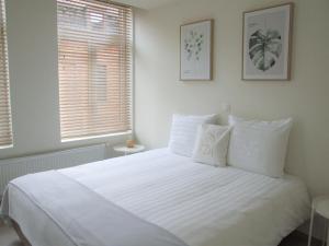 1 Schlafzimmer mit einem großen weißen Bett und 2 Fenstern in der Unterkunft Maison HB in Ypern