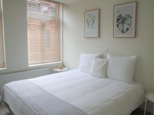 een slaapkamer met een groot wit bed met twee ramen bij Maison HB in Ieper