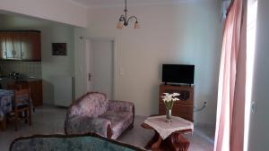 een woonkamer met een stoel en een tafel met een tv bij Vithos Apartment in Kalamata