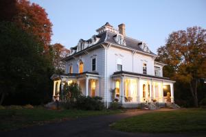 a large white house with its lights on at Proctor Mansion Inn in Wrentham