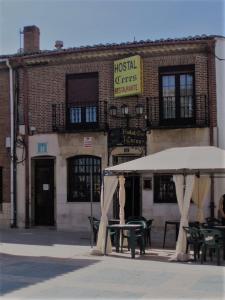 una cafetería con mesas y sombrillas frente a un edificio en Hostal Restaurante Ceres, en Magaz De Pisuerga