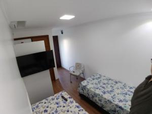 a small room with two beds and a flat screen tv at Mini Kitnet - Santa Cruz do Sul in Santa Cruz do Sul