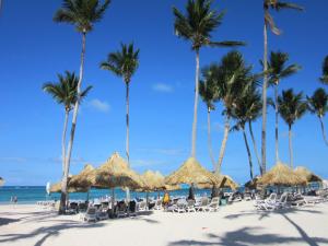 a beach with palm trees and chairs and umbrellas at Coral Village - "Caribbean Cocktails" Deluxe Suites & Pool in Punta Cana