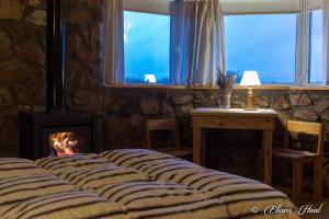 Cama en habitación con chimenea y ventana en La Calandria Casa de Campo en Puerto Madryn