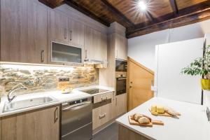 una cocina con armarios de madera y un aparato de acero inoxidable en Albergue O Candil, en Melide