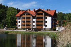 un bâtiment avec un toit rouge à côté d'un lac dans l'établissement Bawaria w Dolinie Szczęścia, à Szklarska Poręba