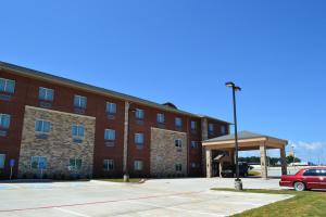 een rode auto geparkeerd voor een gebouw bij Red River Inn and Suites in Thackerville