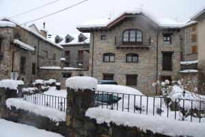 a snow covered house with a car parked in front at Apartamentos Casa Isabale in Biescas