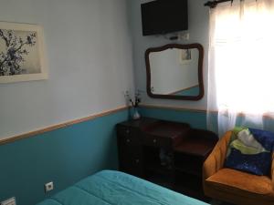1 dormitorio con cama, espejo y silla en Adelaide House, en Praia do Norte