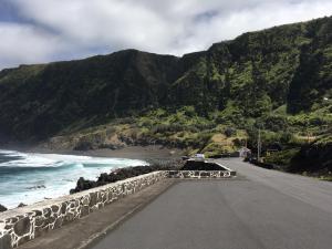 an empty road next to the ocean with mountains at Adelaide House in Praia do Norte