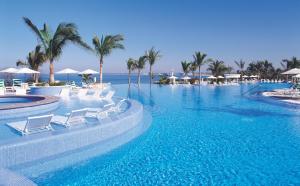 une grande piscine avec des chaises blanches et des palmiers dans l'établissement Pueblo Bonito Emerald Bay Resort & Spa - All Inclusive, à Mazatlán