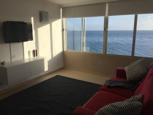- un salon avec un canapé rouge et une grande fenêtre dans l'établissement Ocean Breeze San Agustin, à San Agustín