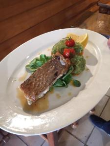 a plate of food with a piece of fish and broccoli at Hôtel Le Porquerollais in Porquerolles