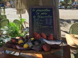 a plate of food on a table with a sign at Hôtel Le Porquerollais in Porquerolles