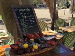 a plate of food on a table with a sign at Hôtel Le Porquerollais in Porquerolles