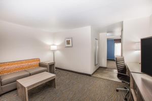 um quarto de hotel com um sofá e uma cadeira em Wingate by Wyndham Louisville Airport Expo Center em Louisville