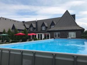 a large blue swimming pool in front of a house at Rezydencja Legrams in Darłowo