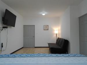 1 dormitorio con 1 cama, 1 silla y TV en MV Suites Suc. Capilla, en Monterrey