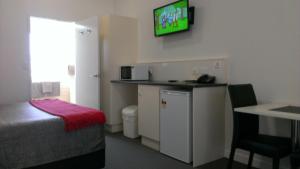 a hotel room with a bed and a television on the wall at Gunnedah Lodge Motel in Gunnedah
