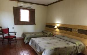 a room with two beds and a chair and a window at Fazenda San Francisco in Pôrto