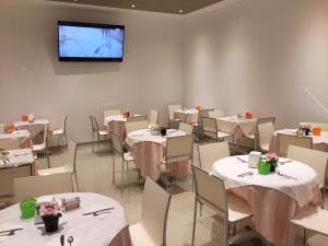 Hotel Bel Soggiorno في جينوا: غرفة طعام مع طاولات وكراسي وتلفزيون