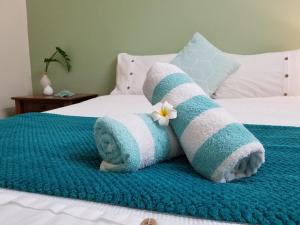 a towel with a flower on top of a bed at Backpackers By The Bay in Airlie Beach
