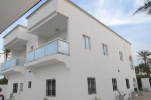 a white building with balconies and palm trees at Drammeh's Villa in Serekunda