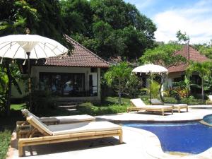 uma piscina com duas espreguiçadeiras e um guarda-sol em Bali Dream House em Amed