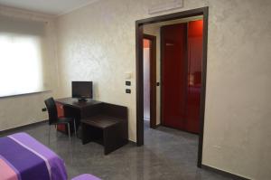 Habitación con escritorio, cama y puerta en Hotel Toscano, en Tarsia