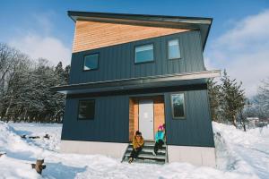 a woman standing outside of a house in the snow at WAGAYA by Hakuba Hotel Group in Hakuba