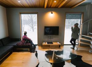 two people sitting in a living room with a tv at WAGAYA by Hakuba Hotel Group in Hakuba