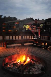 a man sitting on a bench next to a fire at Sunset Bay Resort in Wisconsin Dells