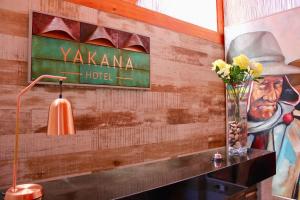 a wall with a sign for a hotel and a vase of flowers at Yakana Hotel in San Pedro de Atacama