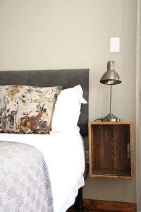 a bed with a pillow and a lamp on a night stand at Avo&Oak Guesthouse in George