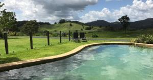 
a large pool of water in front of a lush green hillside at Hillcrest Mountain View Retreat in Crystal Creek
