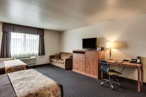a hotel room with a bed and a desk with a television at SureStay Plus Hotel by Best Western Post Falls in Post Falls