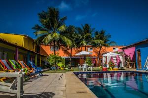 uma piscina num resort com cadeiras e palmeiras em Pousada Vila Nalu em Praia do Francês