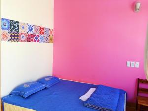 a bedroom with a blue bed with a pink wall at Bot Bien Homestay in Mui Ne