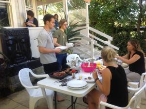 un grupo de personas de pie alrededor de una mesa con comida en Lantana Lodge en Auckland