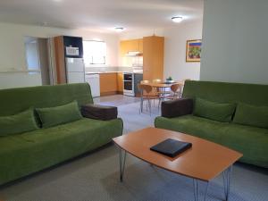 uma sala de estar com dois sofás verdes e uma mesa em Noosa Holiday Accommodation em Noosaville