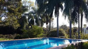 einen Pool in einem Garten mit Palmen in der Unterkunft Casaquinta City Bell in City Bell