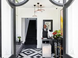 a man in a suit standing at a desk in a hallway at The Manor House at the Queen Victoria Hotel by NEWMARK in Cape Town +84 photos