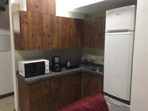 cocina con armarios de madera, microondas y nevera en Apartamento Arco del Cristo, en Cáceres