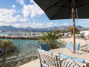 a table with chairs and an umbrella on a beach at 'The View' on Bikini Beach, Seafront, 2 bedroom, Sleeps 4 in Gordonʼs Bay +38 photos