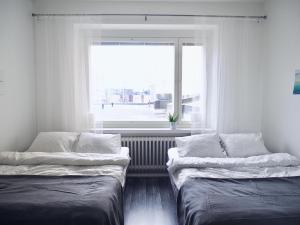 two beds in a room with a window at 2ndhomes Tampere "Koskipuisto" Apartment - Downtown 1BR Apt with Sauna in Tampere