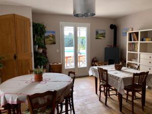 una sala de estar con 2 mesas y sillas y una habitación en Le clos des vergers, en LʼIsle-sur-la-Sorgue